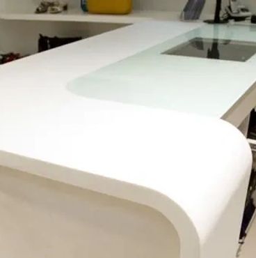 Modern white kitchen island with rounded edges and built-in cooktop.