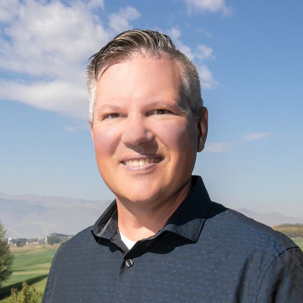 Smiling man outdoors with scenic background.