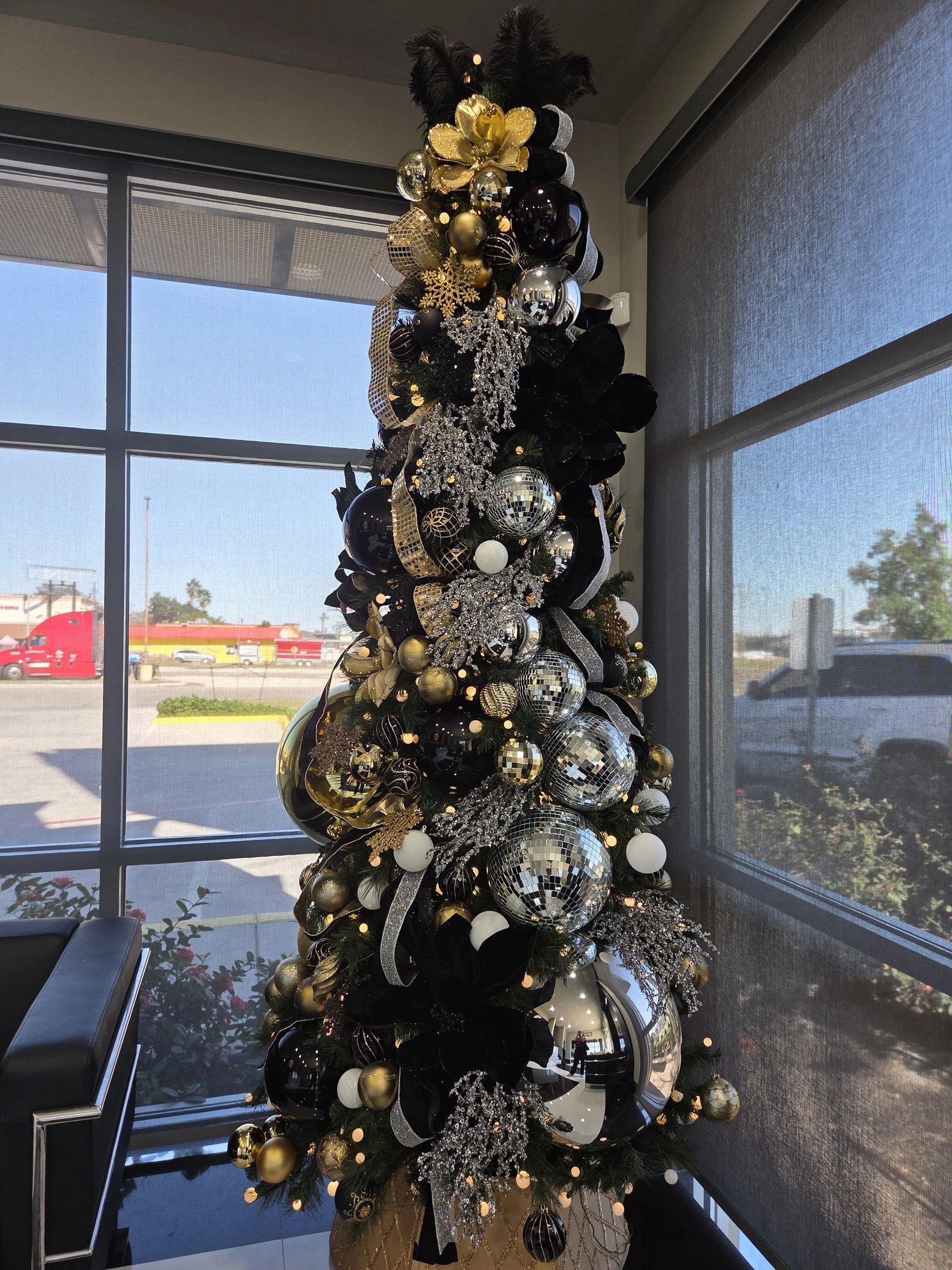 Christmas tree decorated with black, gold, and silver ornaments.