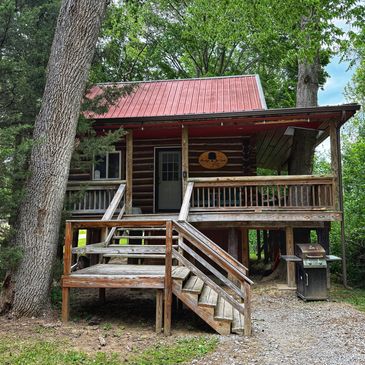 Rustic wooden cabin with red roof in forest.