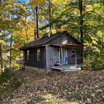 Small rustic cabin surrounded by autumn trees.