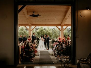 Bride and groom getting married under wood canopy.