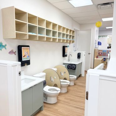 Clean and organized kids' bathroom with child-sized toilets and sinks.