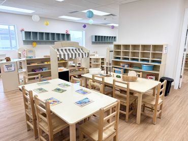 Bright and organized preschool classroom with wooden furniture and learning centers.