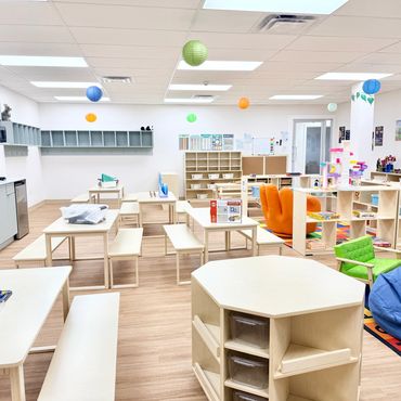 Bright and colorful preschool classroom with wooden tables and hanging lanterns.