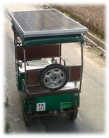 Green auto-rickshaw with solar panels on top.