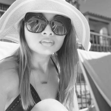 Woman wearing large sunglasses and a sunhat outdoors.