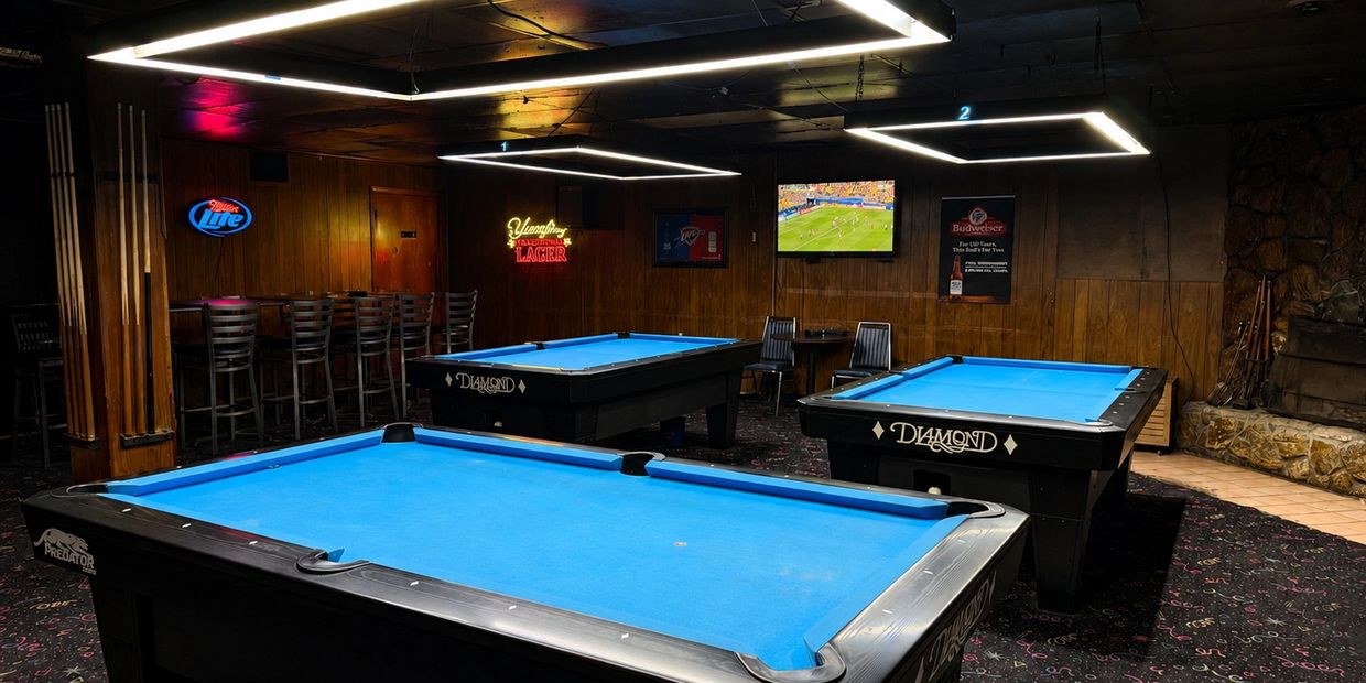 Pool hall with bright blue tables and neon signs.