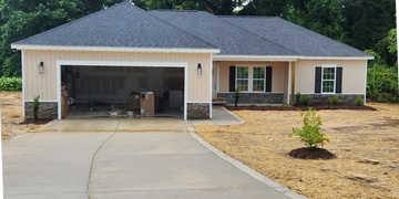 Newly constructed single-story house with an open garage and a concrete driveway.