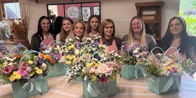 Group of women with colorful flower arrangements.