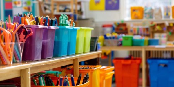 Colorful containers filled with school supplies on a classroom table.