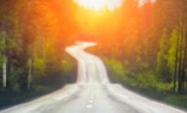 A road with the word RECOVERY painted on it, leading into a bright sunrise.
