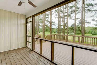 Spacious screened porch with wooden deck overlooking trees and greenery.
