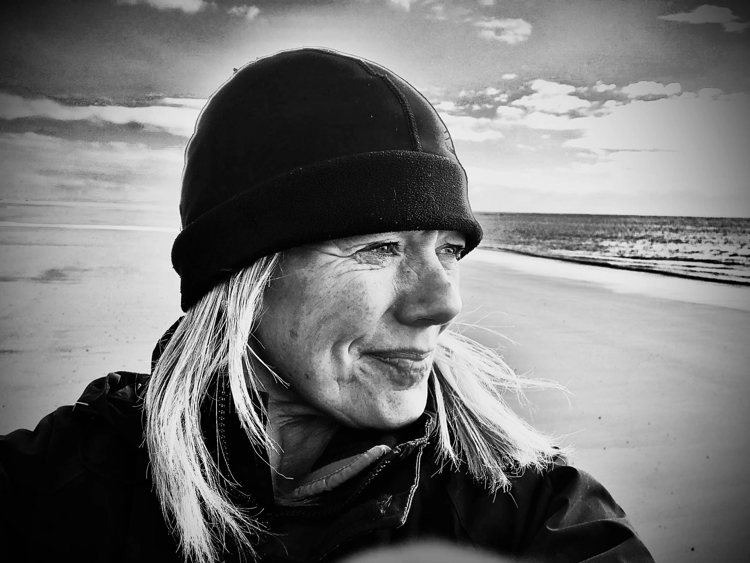 Woman in a black hat enjoying a serene beach moment.