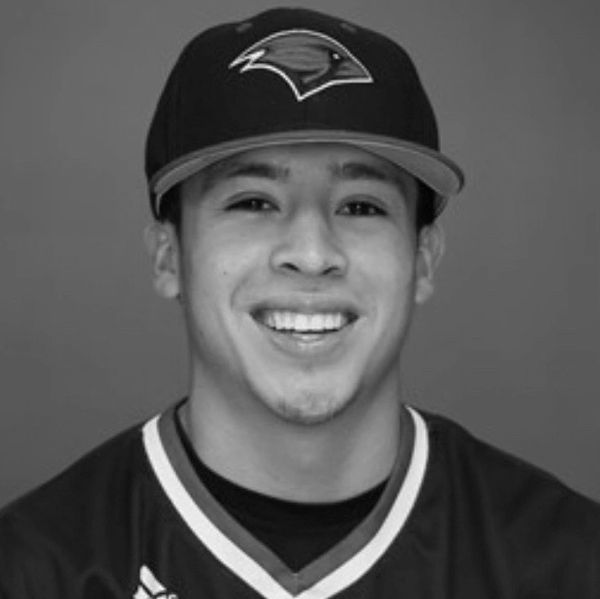 Young man smiling wearing a baseball cap and jersey.
