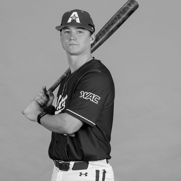 Baseball player posing with bat on shoulder.
