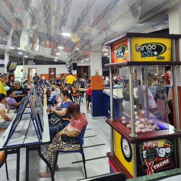 Grupo de personas jugando bingo, al lado maquina de bingo lotto