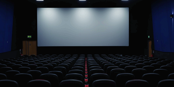 Empty movie theater with rows of seats facing a large screen.