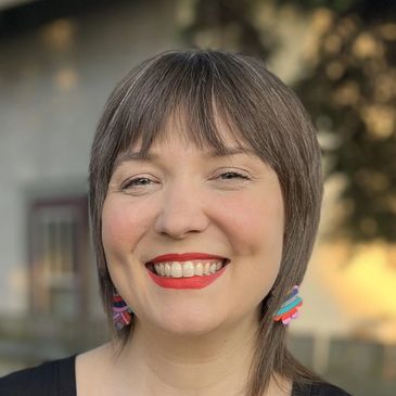 Smiling woman with short hair and bright lipstick.