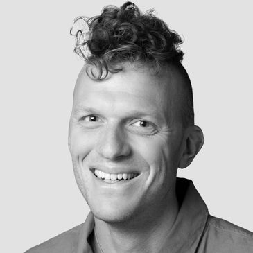 Smiling man with curly high-top hairstyle.