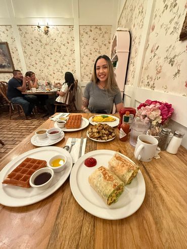 Woman sitting at a table with breakfast foods in front of her.