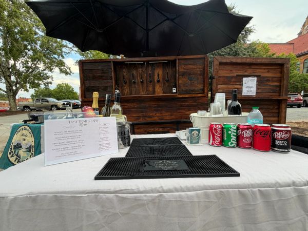 Outdoor bar setup with drinks and soda cans.