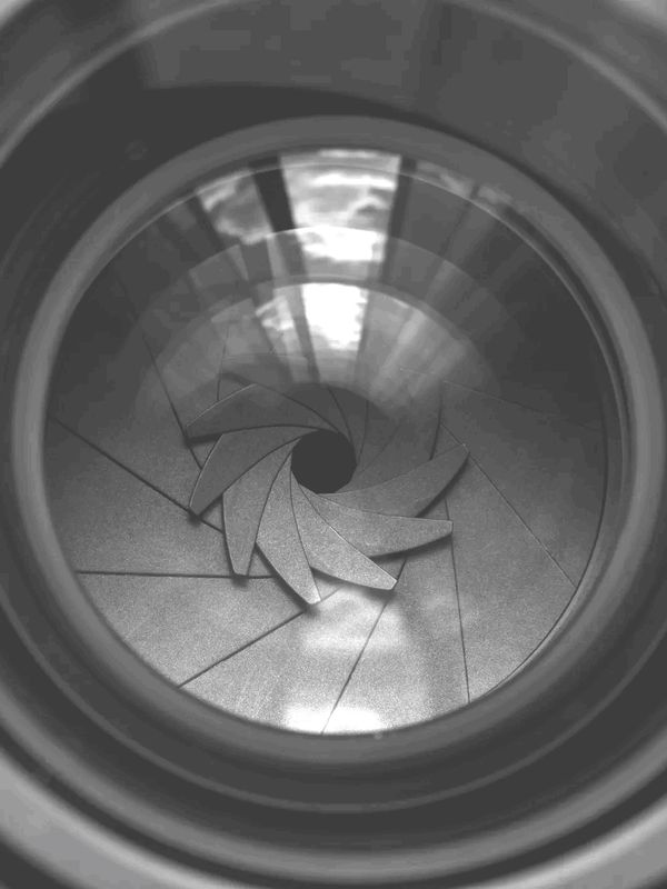 Close-up of a camera lens aperture blades in black and white.