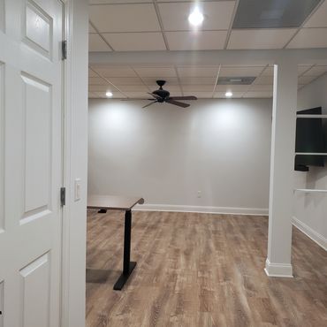 Basement remodel with waterproofed walls, light gray paint, white trim, and cinnamon wood-look LVP f
