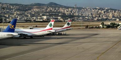 Airplanes parked at an airport with a city and hills in the background.
