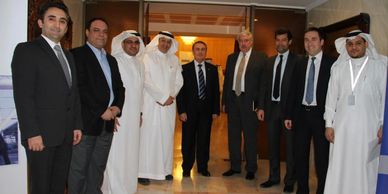 Group of men in formal and traditional Middle Eastern attire posing indoors.
