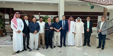 A group of men posing in a formal indoor setting with traditional and business attire.