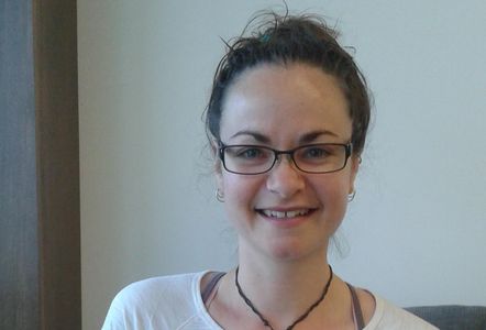 Smiling woman with glasses and tied-up hair.