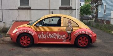 Colorful Volkswagen Beetle advertising a house buying service.