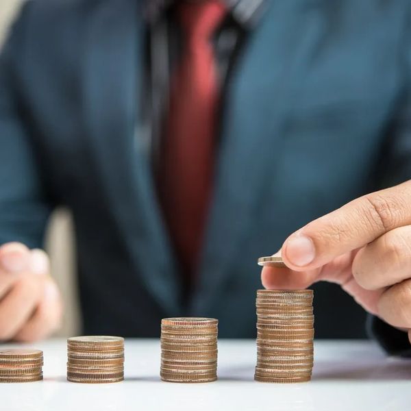 Person stacking coins in growing piles, symbolizing financial growth.