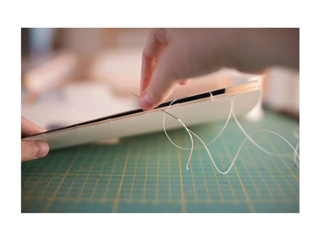 Person sewing pages for book binding.
