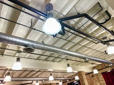 A ceiling with exposed pipes and conduits in an industrial setting.