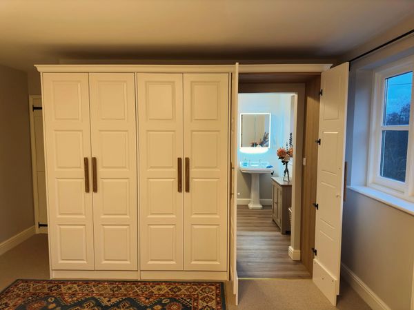 A wardrobe with a hidden door leading to a bathroom.
