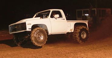 White off-road truck driving at night on dirt.