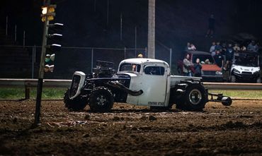 A powerful modified truck named Strategic Attack at a nighttime dirt track event.