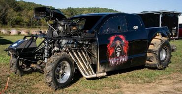 Black off-road racing truck with skull and flames decal.