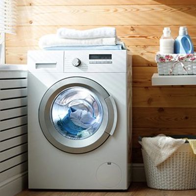A modern front-loading washing machine in a wooden laundry room.