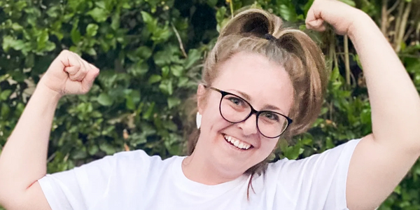 Smiling woman flexing muscles wearing a 'Strong Girls Club' t-shirt.