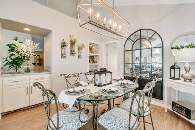 Elegant dining room with glass table and decorative plants.