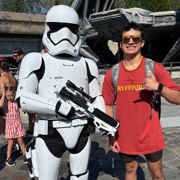 Person posing with a Stormtrooper at a theme park.