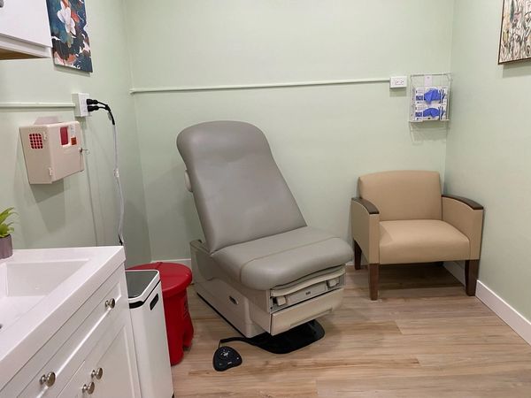 Patient exam room with accessible exam table and guest chair