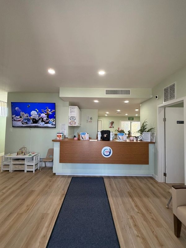 Reception area with wood floors and counter, with a childrens table and chairs