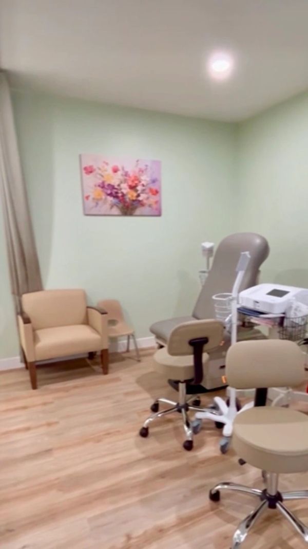Patient exam room with wood floors, green walls and picture with pink flowers