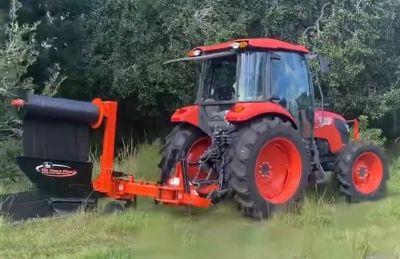 Red tractor with an attached farming implement in a grassy area.