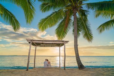 Honeymoon couple sitting under a gazebo watching the sunset at LUX* Le Morne Mauritius 