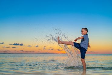 Sunset family photoshoot of child having fun with splash of water in Mauritius during sunset.
